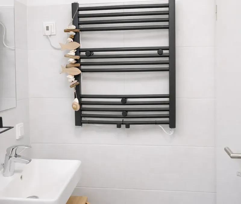 Badezimmer im Ferienhaus Seeblick Badezimmer im Ferienhaus Seeblick mit Waschbecken und schwarzem Handtuchheizkörper.