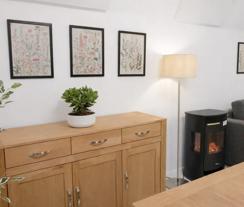 Sideboard im Wohnbereich vom Ferienhaus Seeblick Wohnbereich im Ferienhaus Seeblick mit Sideboard, Pflanze, Bildern und Kaminofen.
