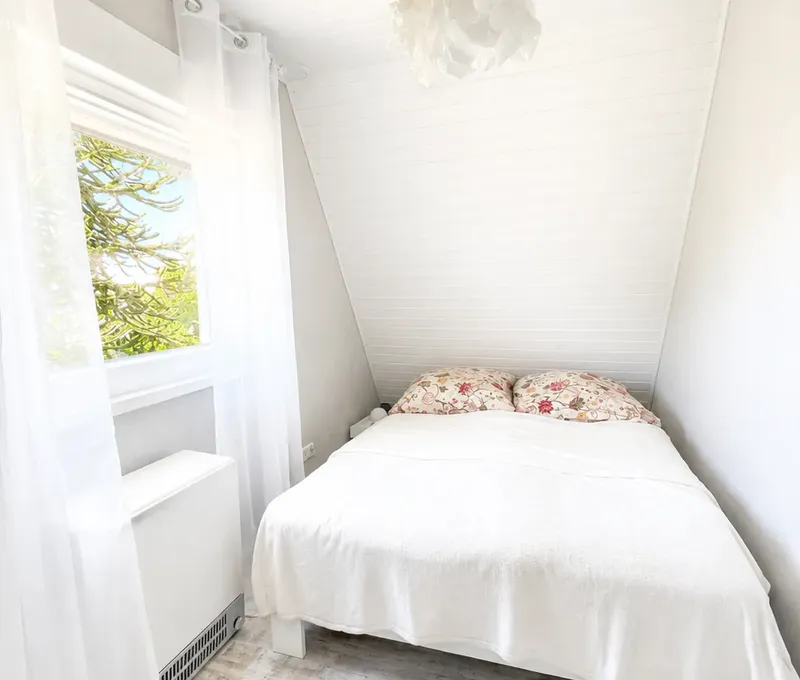 Doppelbett im Haus am See Helles Schlafzimmer im Haus am See mit Doppelbett und Fenster.