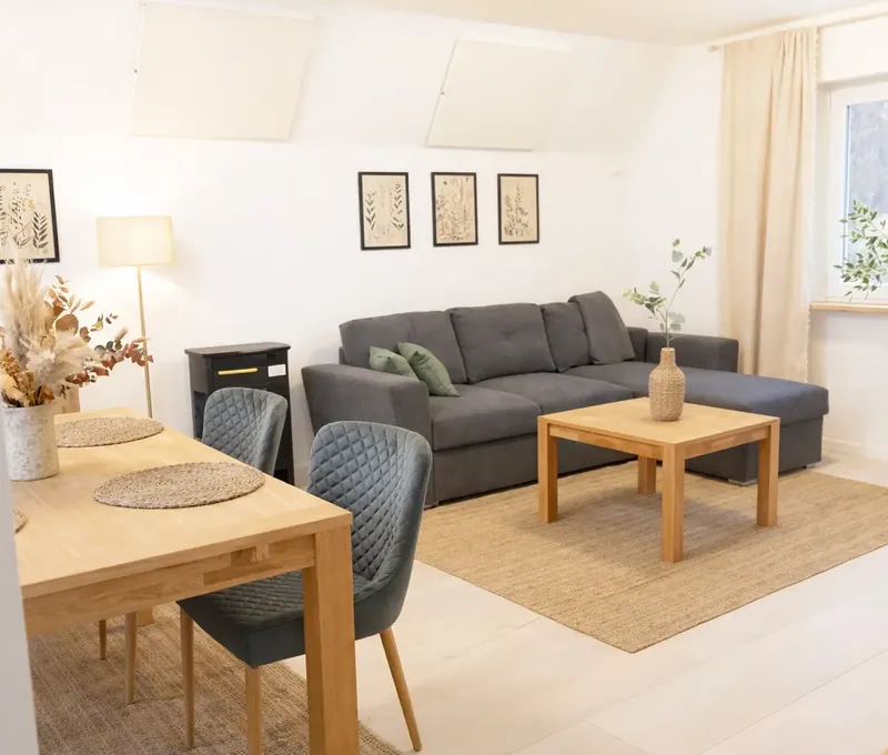 Wohnzimmer mit Sofa im Ferienhaus Seeblick Wohnzimmer im Ferienhaus Seeblick mit Sofa, Couchtisch, Bildern und hellem Fenster.