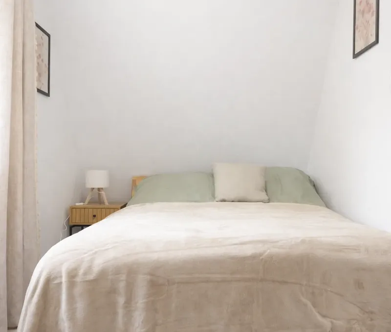 Bett im Schlafzimmer vom Ferienhaus Seeblick Schlafzimmer im Ferienhaus Seeblick mit Bett, Nachttisch und hellen Vorhängen.