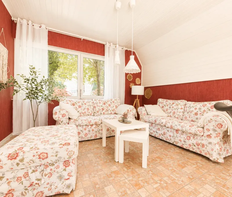Wohnzimmer im Haus am See Gemutliches Wohnzimmer im Haus am See mit Sofa, Couchtisch und roten Akzentwaenden.