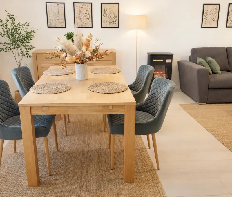 Essbereich im Ferienhaus Seeblick Essbereich im Ferienhaus Seeblick mit Holztisch, gepolsterten Stühlen und Sofa im Hintergrund.