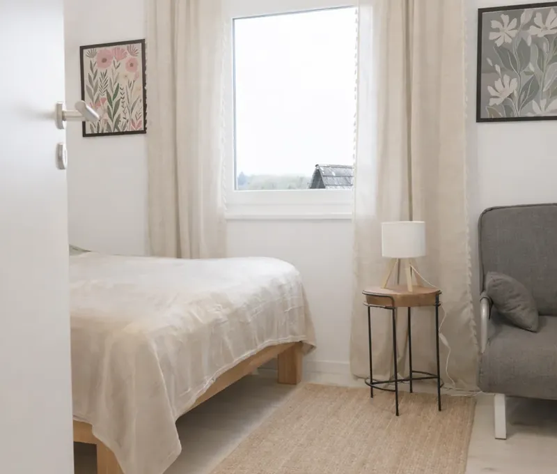 Schlafzimmer im Ferienhaus Seeblick Helles Schlafzimmer im Ferienhaus Seeblick mit Doppelbett, Fenster und kleinem Stuhl.